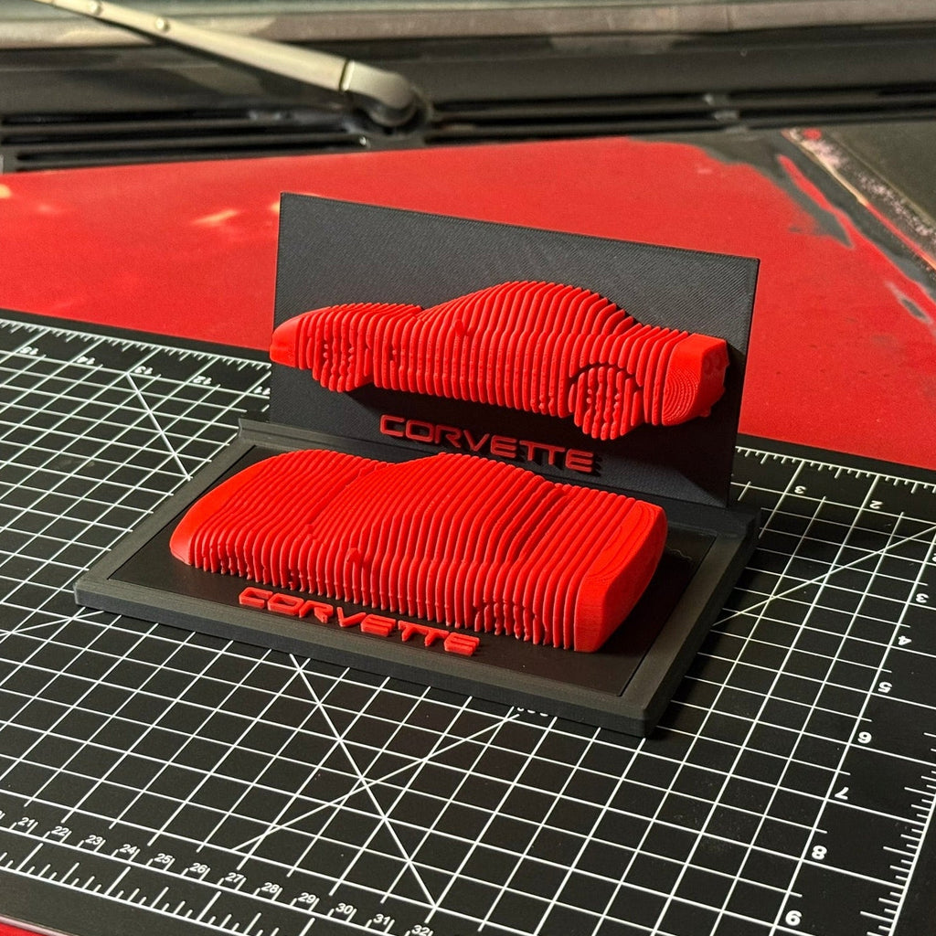 Red car parts on a black Corvette stand with a grid surface underneath