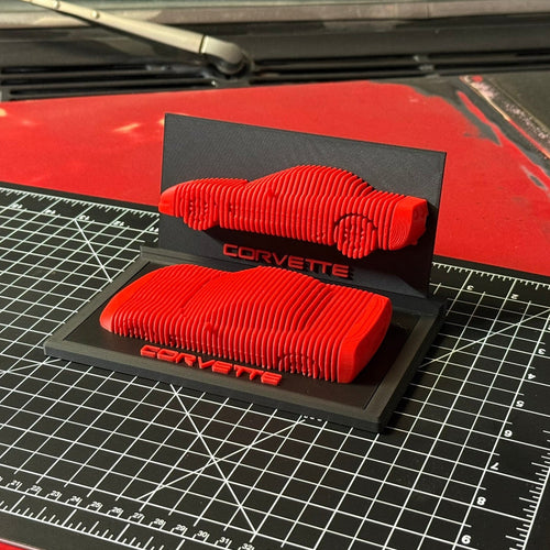 Red car parts on a black Corvette stand with a grid surface underneath