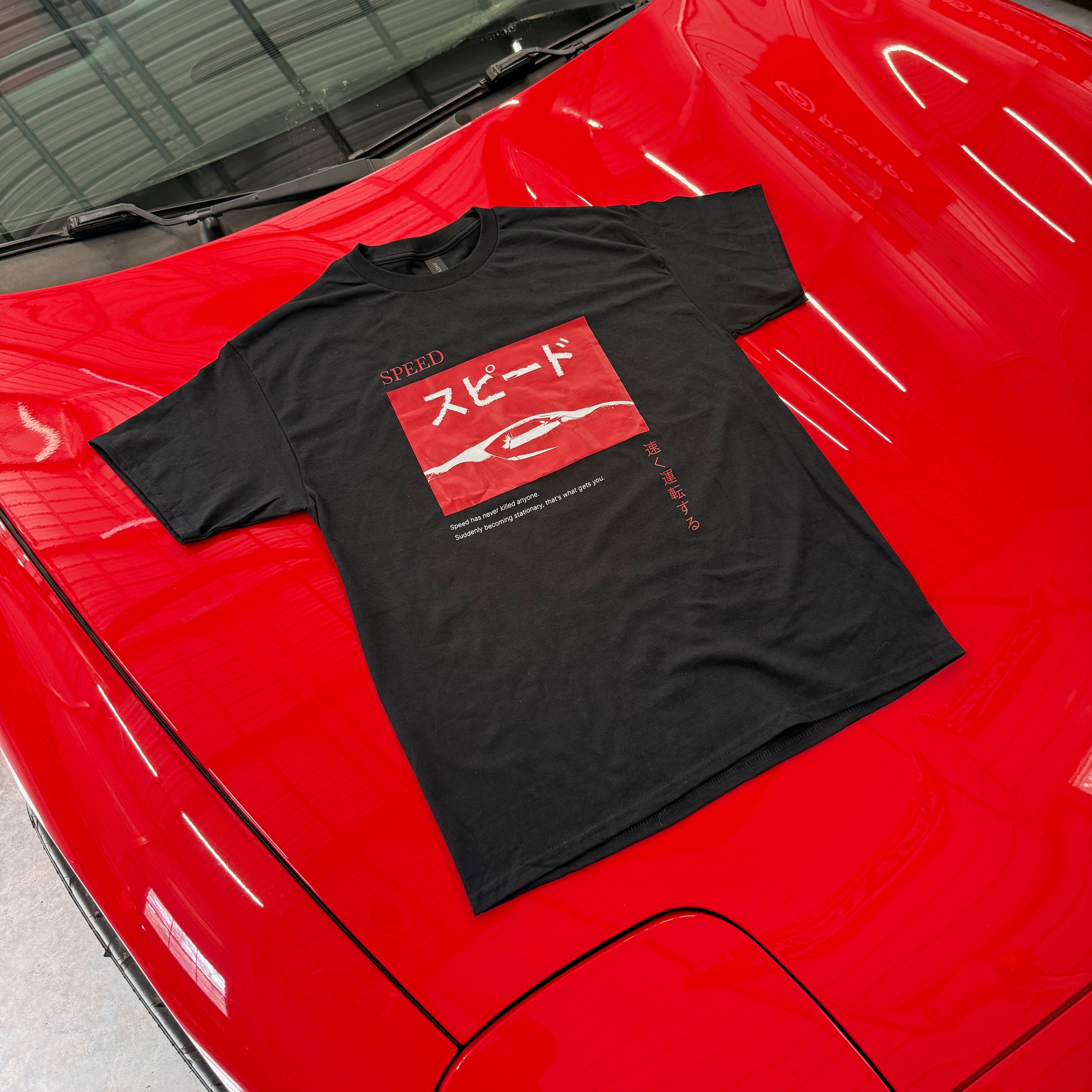 Black t-shirt with red graphic on a red car